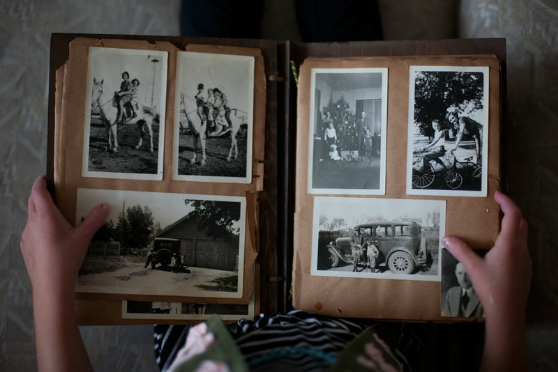 Hands holding an open vintage photo album with sepia family photos